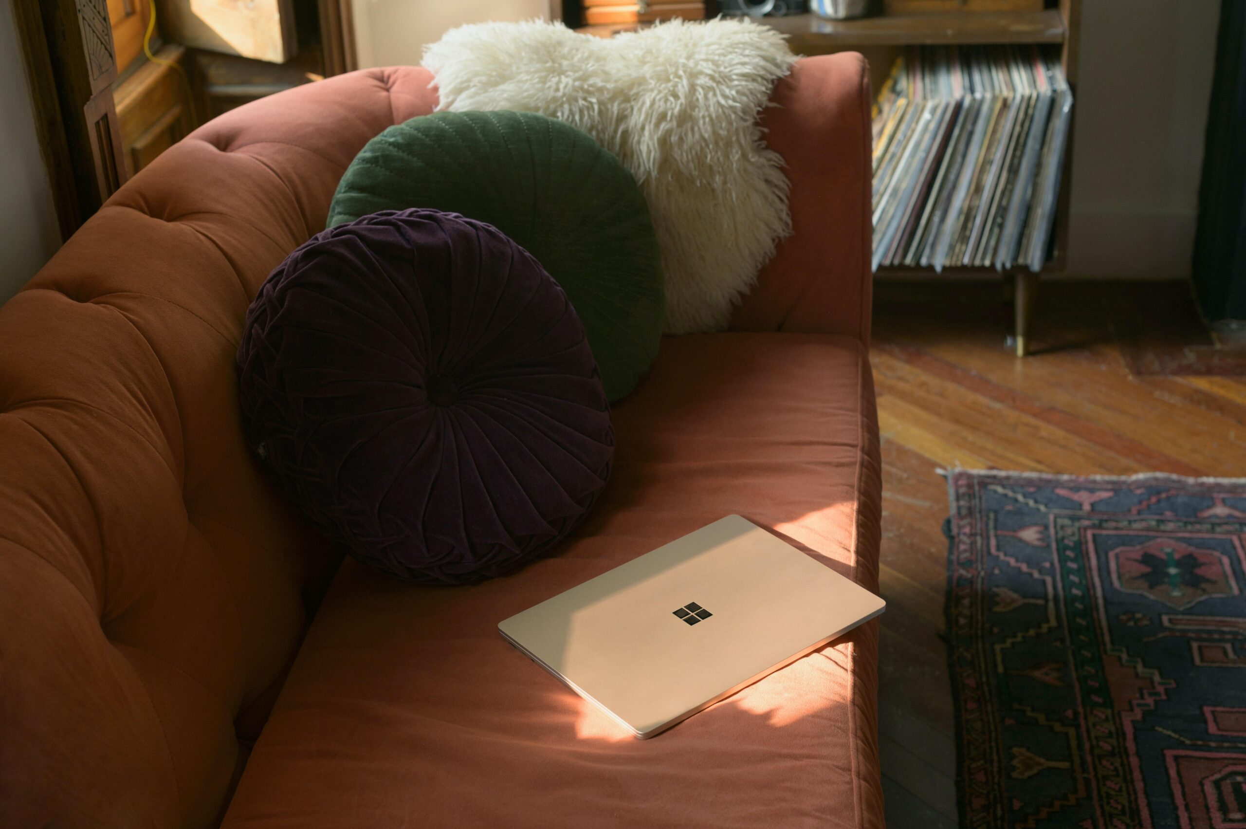 Orange couch with pillows and a laptop on top of it